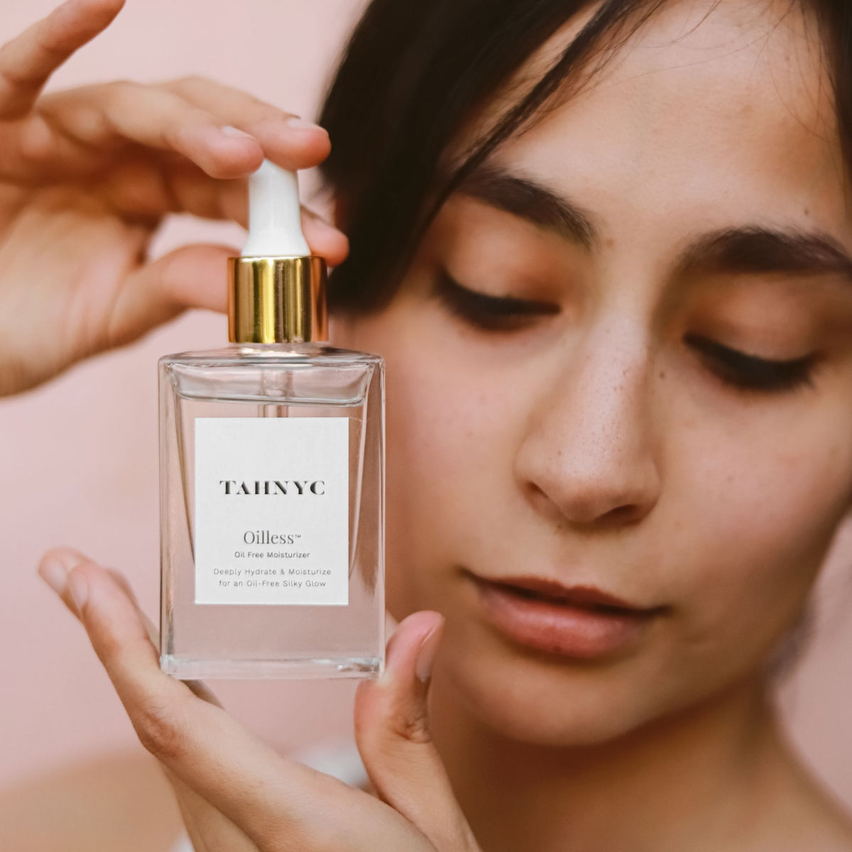 Oilless Moisturizer held by hand, next to face.